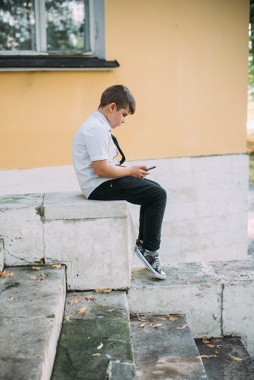 a White boy sitting and using a cell phone 1