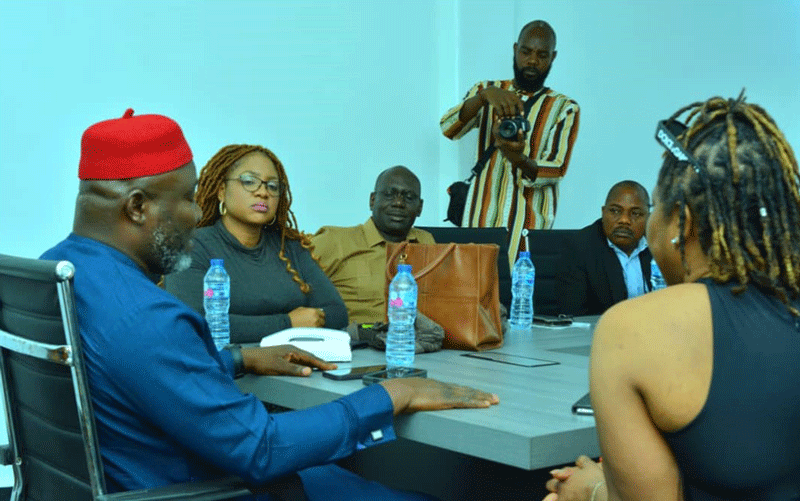 Chief Tony Amechi in blue native attire and a red cap sitting close to Mrs. Evelyn Nomayo